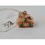 A 18ct gold charm in the form of a house and set with green stones 5.1g