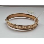 A scroll engraved rolled gold bangle