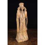 A 17th Century Wood Carving of an Acolyte wearing a cap, cloak and long robe,