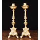 A Pair of Baroque Bronze Candlesticks: The tulip-head candle sockets within dished drip pans on