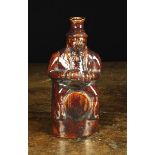 An Early 19th Century Dark Treacle Glazed Bottle moulded in the form of a man straddling a barrel,