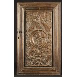 A 16th Century Carved Oak Romayne Panel set in a later reeded door frame.