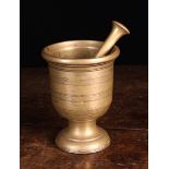 An 18th Century Brass Pestle and Mortar with engine turned decoration and a footed base,