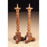 A Pair of Italian Turned Wooden Candlesticks with knopped baluster stems on carved triform bases