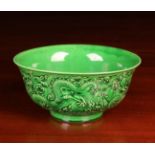 A Chinese Green Glazed Bowl relief moulded with three writhing dragons amongst scrolling cloud