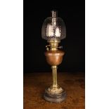 A Victorian Brass & Copper Oil Lamp with moulded clear glass shade above a copper font raised on a