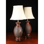 A Pair of Oriental Style Patinated Cast Metal Lamps with cream silk shades.