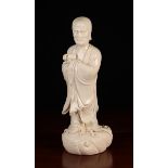 A White Glazed Oriental Figure of a Scholar or Deity holding a slipper in his hand and stood on a