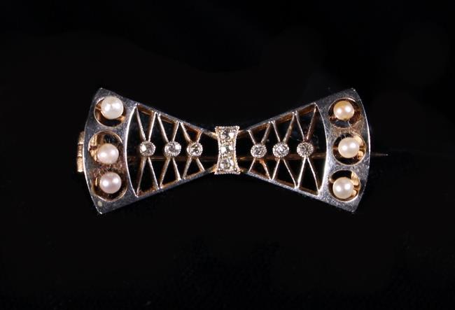 A 15 Carat Gold Bow Brooch adorned with diamond chips and seed pearls.