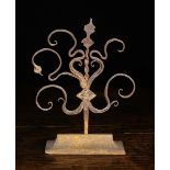A 17th Century Wrought Iron Finial decorated with scroll work stems either side and mounted on a
