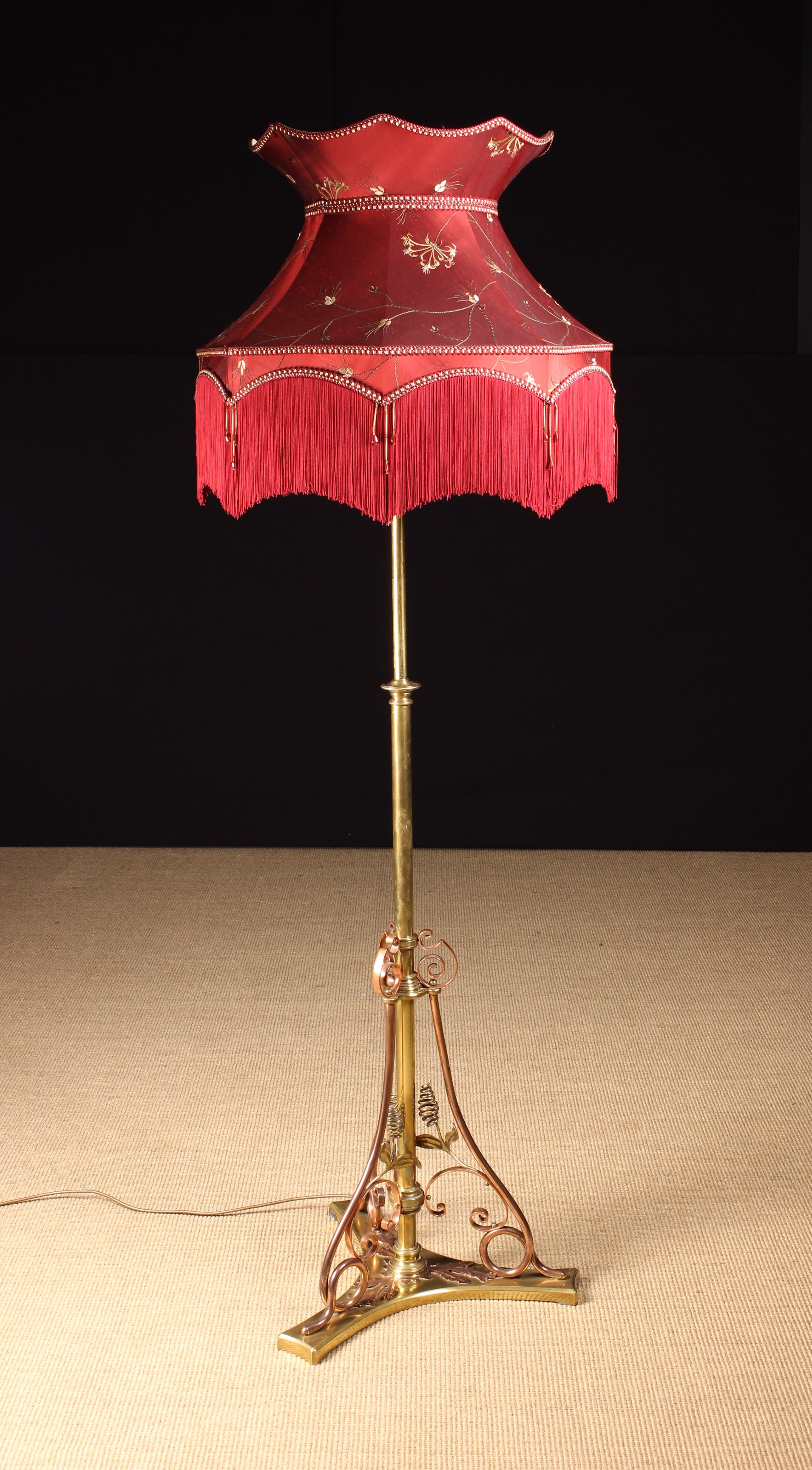 An Arts & Crafts Brass & Copper Telescopic Standard Lamp with a fringed crimson silk shade