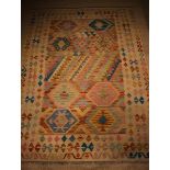 A Kelim Rug woven in a subtle palette of warm colours on a beige ground,