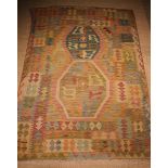 A Kelim Rug woven in a subtle palette of warm colours on a beige ground,