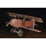 A Vintage Carved Wooden Bi-plane with rubber tyred wheels and a metal propeller,