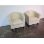 A pair of faux leather cream tub chairs, some usage marks but generally good