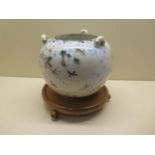 An Oriental globe shaped hanging bird and prunus decorated censor on a turned wooden stand, globe
