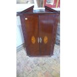 A Georgian mahogany corner cupboard with two shell inlaid doors and a painted interior, 113cm tall x