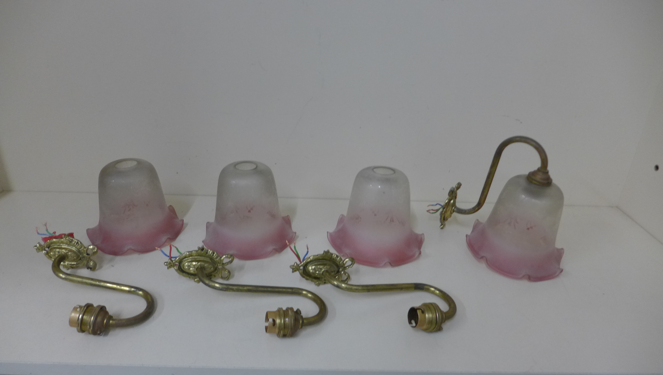 Four brass wall lights with Cranberry tinted shades, shades 12cm x 13cm, all in generally good