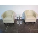 A pair of faux leather cream tub chairs with a glass top coffee table, 49cm tall x 53cm, some