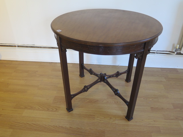 An Edwardian mahogany circular window table with a blind fretwork frieze and fretwork stretchers -