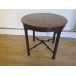 An Edwardian mahogany circular window table with a blind fretwork frieze and fretwork stretchers -