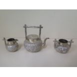 A Chinese silver three piece embossed tea set by Wang Hing marked WH90, the teapot with folding