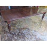 A late Victorian walnut two leaf wind out dining table on reeded legs - height 74cm x width 122cm,