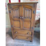 An oak linen fold cupboard with two doors over two drawers having panelled sides - Height 123cm x