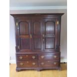 An 18th century oak cupboard on chest with two panelled doors above four drawers on shaped bracket