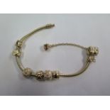 A Pandora 14ct yellow gold bracelet with six charms - approx 17cm long - approx 32.2 grams - in good