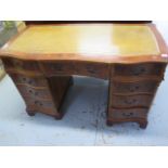 A modern yew wood effect nine drawer twin pedestal desk with a shaped top and leather inset, 78cm