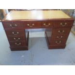 A good quality modern mahogany desk with a leather inset top above two slides and nine drawers,