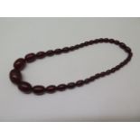 A string of cherry amber beads, approx 40cm long, largest bead 20mm x 14mm, total weight approx 23