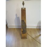 A beautiful gold covered obelisk shaped lamp with defined intricate pattern and floral design
