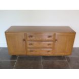 A light Elm Ercol sideboard with two doors and three central drawers on caster, 69cm tall x 156cm