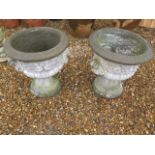 A pair of stone effect concrete urns on stands, 62cm tall x 56cm diameter, some chipping to bases