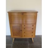 A light Elm Ercol cabinet with a fall front above four drawers and a cupboard, 117cm tall x 98cm x