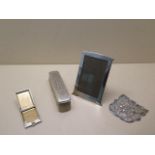 A silver framed photograph frame, 15cm x 10cm, a silver back brush and a silver matchbook holder,