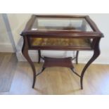 An Edwardian mahogany bijouterie display table with a lift up top on shaped legs united by an