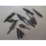 A collection of ten metal arrowheads with aged patinated finish