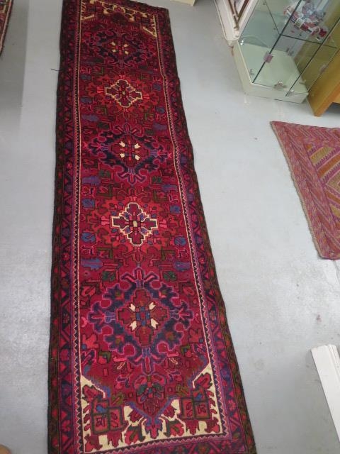 A hand woven vintage Persian Heriz runner with medallion design in vibrant colours, 310cm x 83cm