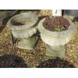 A pair of stone effect concrete garden urns on stands, 40cm tall x 38cm diameter