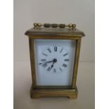 A brass carriage clock, 12cm tall, running, dial good, one small chip to glass door
