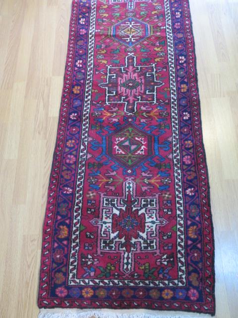 A hand knotted woollen runner with a red field, generally good condition, 340cm x 66cm - Image 2 of 4