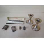 A pair of dwarf weighted silver candlesticks, 2 silver vestas, a silver pencil and 2 thimbles