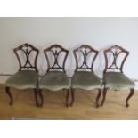 A set of four Victorian walnut side chairs with upholstered seats on cabriole shaped front legs, all