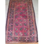 A Turkman hand woven woollen rug with a ref field, 180cm x 114cm, in good condition