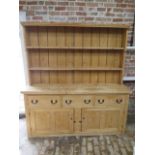 A 19th century stripped pine dresser with an open rack top above three drawers and two cupboard