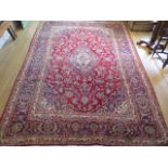 A rich red ground hand woven woollen full pile Persian Kashan carpet with traditional floral