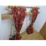 A decorative gilt and red curtain pole with red and gilt lined foliate curtains with rope ties, pole